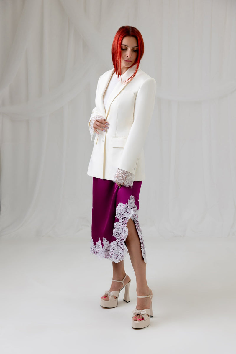 Model wearing the Ivory Muse Blazer with a burgundy lace skirt, elegant profile view