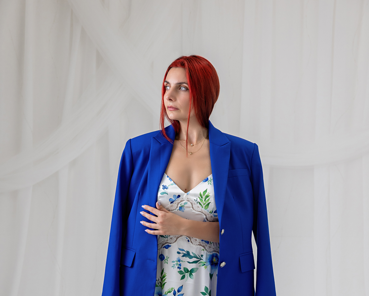 Model wearing the cobalt blue blazer with a floral maxi dress, side view