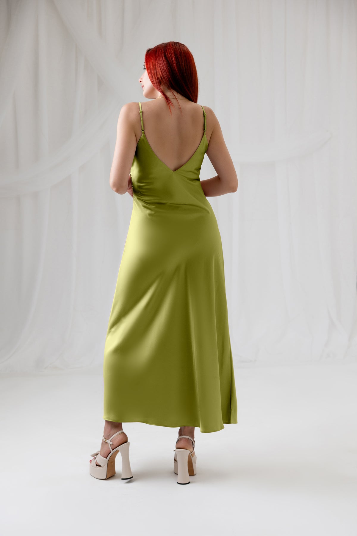 Model wearing the House of Lluvie' green satin slip dress, full-length back view
