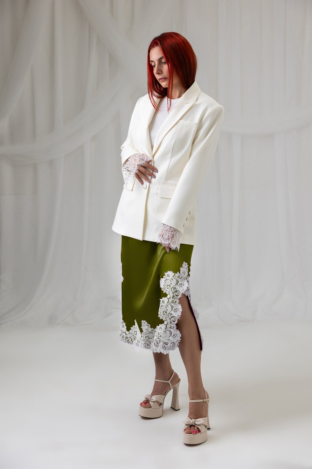 Model wearing the green satin midi skirt with ivory lace hem, side view