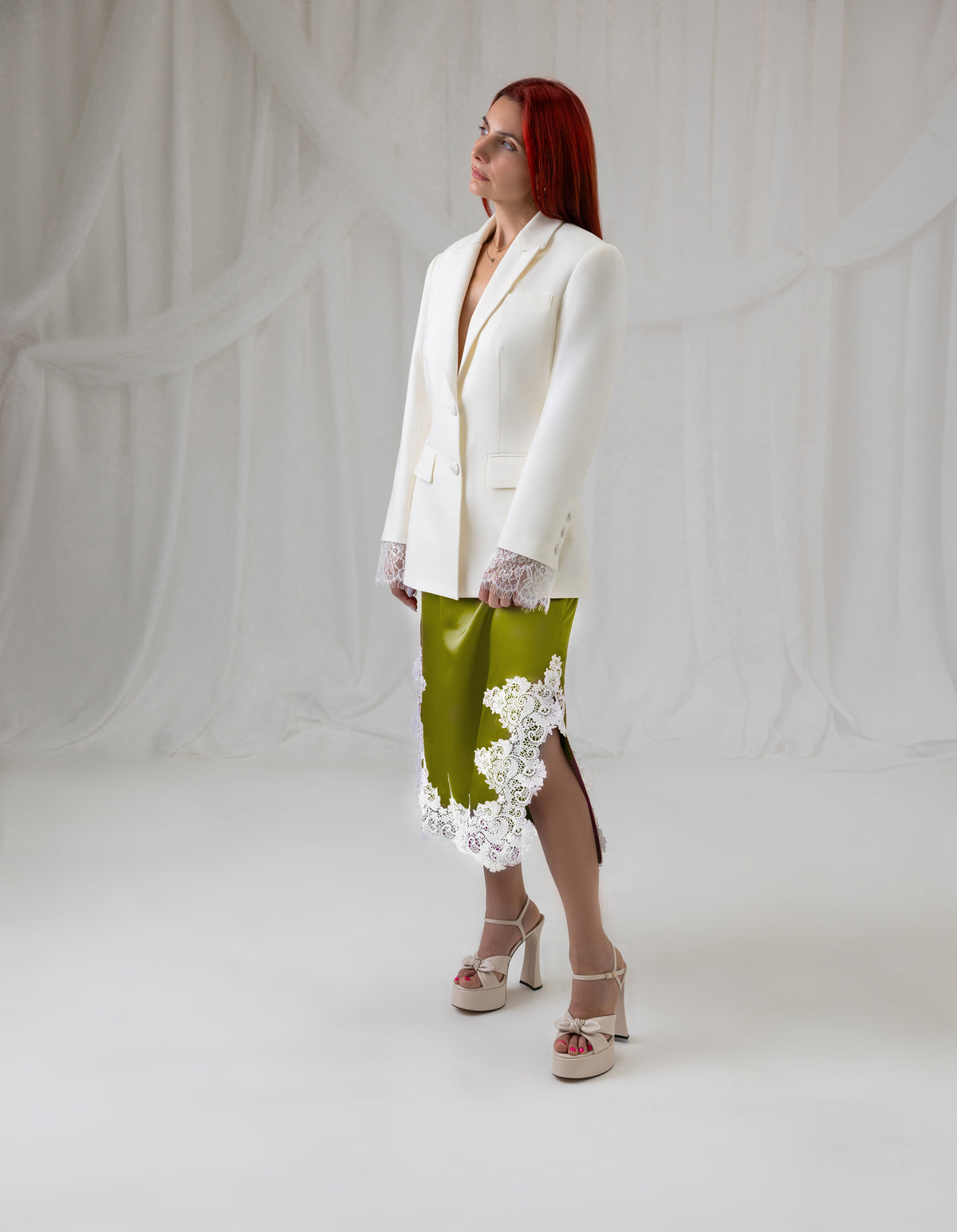 Model wearing the House of Lluvie' green satin lace midi skirt styled with an ivory blazer