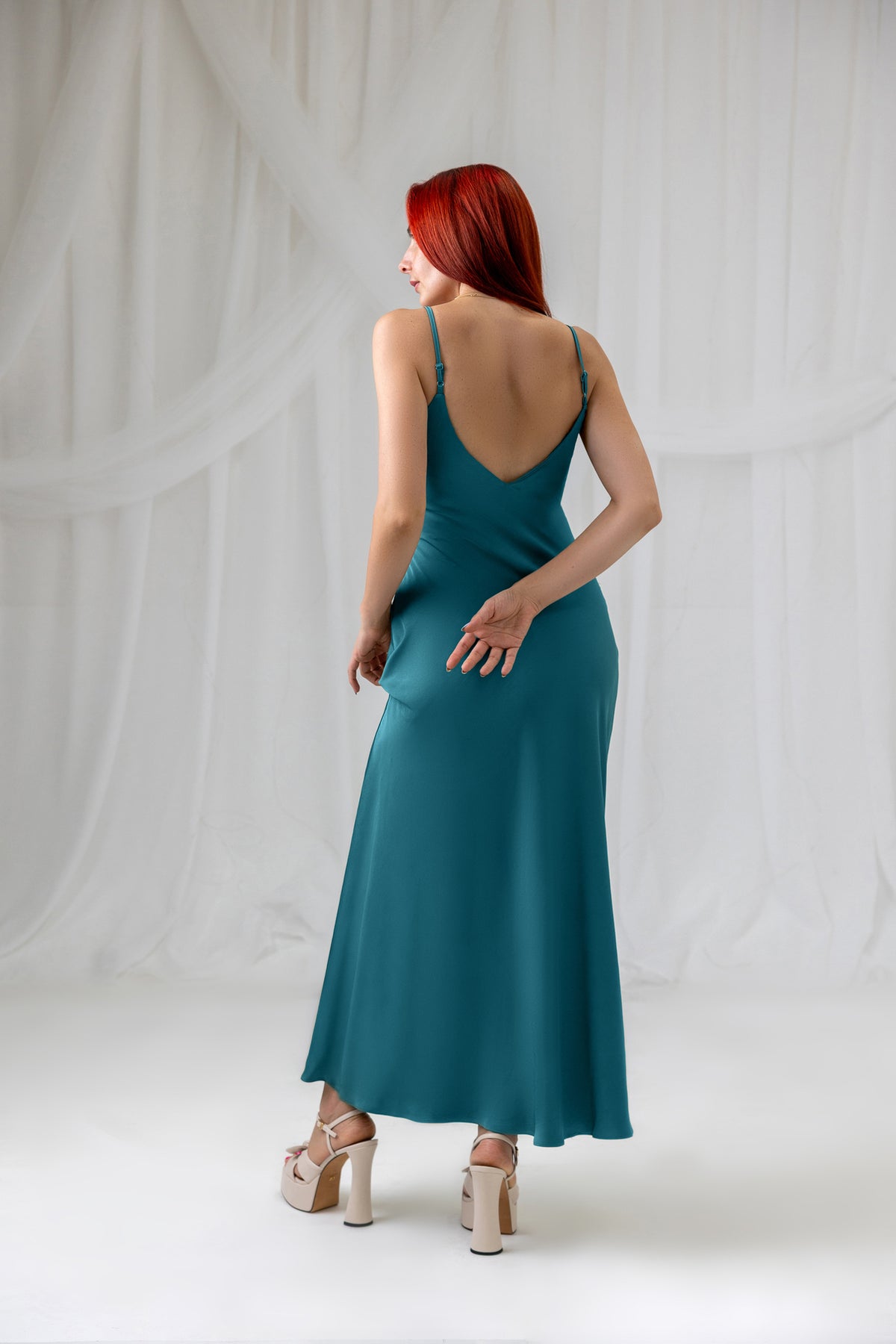 Model wearing the House of Lluvie' teal satin slip dress, back styling view